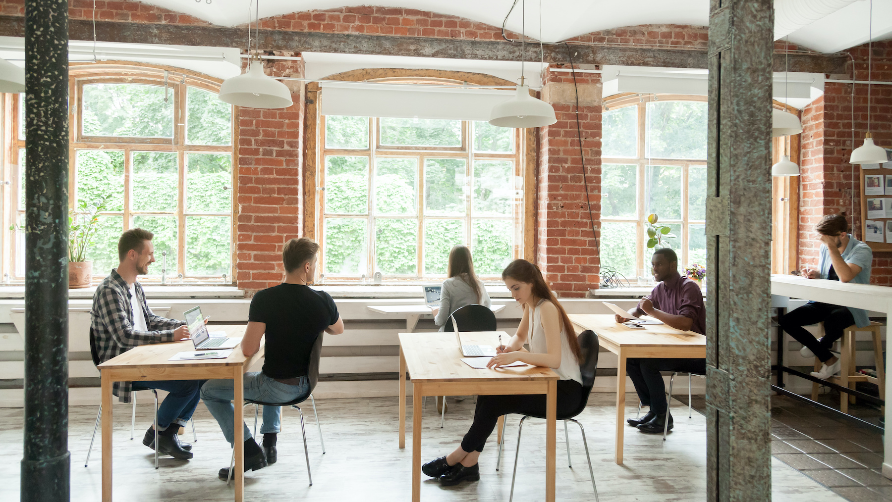Multiracial people working and talking in modern co-working spac