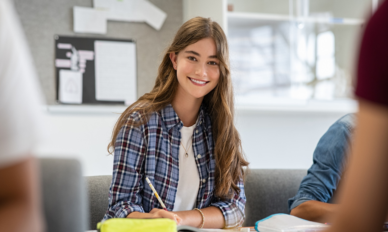 Smiling college girl studying in classroom